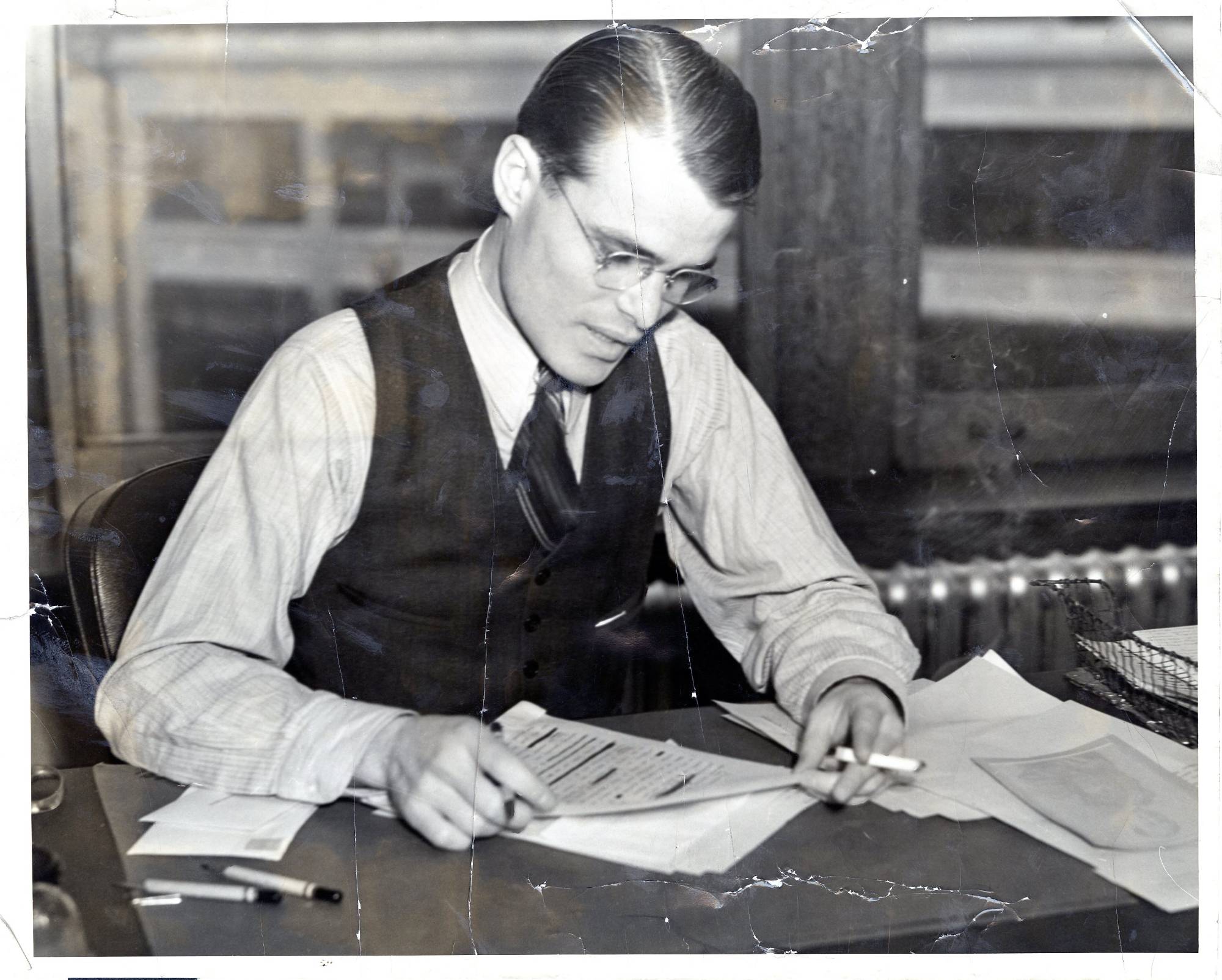 Ralph Hauenstein working at his editors desk in a vest